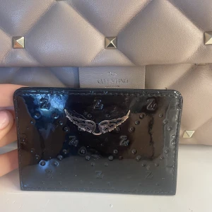 Zadig plånbok/korthållare - Säljer min zadig korthållare då jag har fått en ny! Köpt i nice, Frankrike i maj 2022, kvitto, dustbag och påse medföljer. Köptes för 85€ vilket motsvarar ungefär 1000kr. Den har skador som syns på andra bilden, men det syns inte när man har korten i!