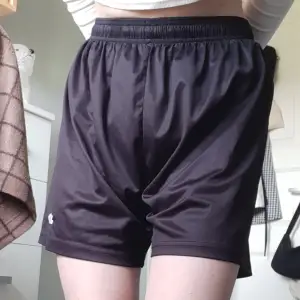Svarta shorts i glansigt material med lite längre shortsben. Köpta secondhand men används inte längre. Skriv för mer info och fler bilder🌸
