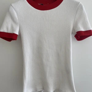 T shirt  - Vit t shirt med lite rött på nacken och armarna säljer pgr av att jag knappt använder den 