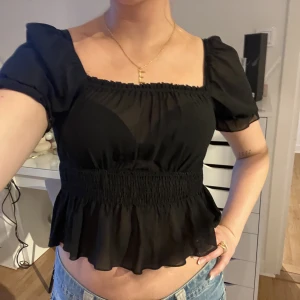 Svart blus - Svart blus från nakd, lite genomskinlig som ni kan se på bilden! Säljer pga för liten för mig (därav är den kort på mig). Knappt använd🩷