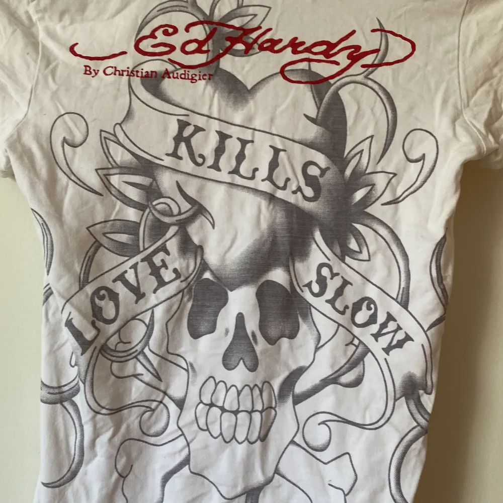 En vit t-shirt från Ed Hardy, med ett fint tryck med texten  ”love kills slowly” 💃🏼  Har även tryck på baksidan!  Står ingen storlek men skulle uppskatta till en xs/s men har stretch så passar nog även M🌸   Fint men använt skick ✨. T-shirts.