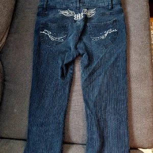 Y2k lågmidjade jeans - Lågmidjade flared mörkgrå jeans med vita motiv baktill. Strl 38