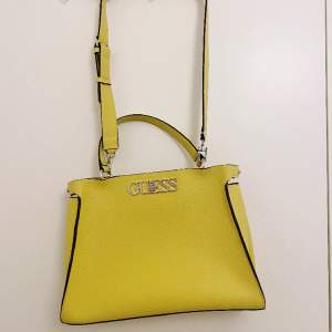 Smidig axel/handväska från Guess i en härlig gul färg. Två separata fack som man kan öppna var för sig. Har en missfärgning på baksidan (se bild) som ev går att tvätta bort