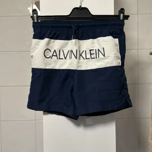 Calvin klein vad byxor - Badbyxor från Calvin Klein i storlek 12/14 i marinblå och vit 