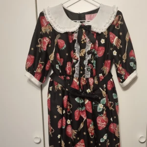 Angelic pretty lolita klänning - Angelic pretty royal crown berry OP i svart med avtagbart bälte. Det finns små skador på klänningen, se sista bilden för skadorna. Mått: byst: 93cm midja: 78cm längd: 92cm + 3cm spets. Möts upp i vänersborg.