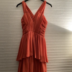 Klänning - Kort fin klänning med volanger, slutar ovanför knäna. Oanvänd men köpt på second hand 