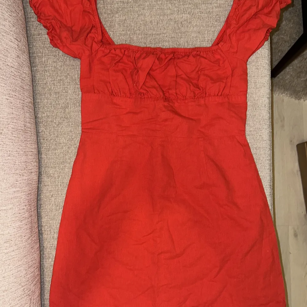 Röd, kort klänning i linne, storlek medium/38, sparsamt använd. Klänningar.