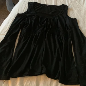 Tröja - Svart tröja med öppen axel, market är avklippt. Köpt second hand och har andvänt fåtal gånger. Står ingen storlek men passar som S
