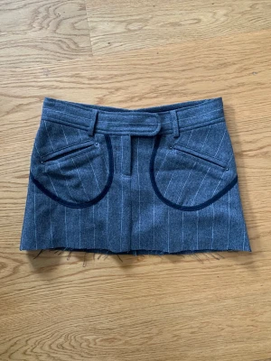 Kort kjol i ullmaterial  - Supersöt minikjol i fint material med fina detaljer. Inga tecken på användning.