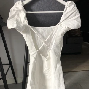 Vit klänning med öppen rygg  - Säljer nu denna vita klänning som passar perfekt till studenten! Använd 1 gång så i väldigt bra skick! Den är ifrån Zara i storlek XS! Fler bilder kan skickas vid behov!