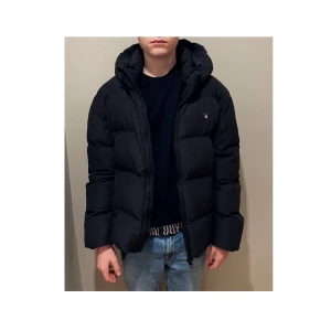 Superfin Gant Puffer Jacket - Säljer denna fina vinterjacka som är sparsamt använd och i toppskick! Nypris 2000kr Den quiltade jackan har fickor med lock, avtagbar kapuschong, en innerficka med dragkedja och ikoniska sköldlogotyp på bröstet. Den är boxig, unisex så att den passar alla