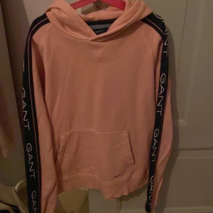 Gant hoodie - Rosa hoodie med blåa detaljer. En stilren hoodie från GANT. Sparsamt använd och inga defekter eller tecken på användning. Bra material och kvalité. Nypris 799 kr och mitt utgångspris 450 kr. Priset kan diskuteras.