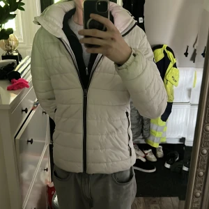 Superdry  Jacka  - En bra jacka till vintern som inte längre kommer till andvändning. Finns ett litet fel som man kan se på bild ett ett knäppe till armén har gått av men inga andra skavanker på jackan 