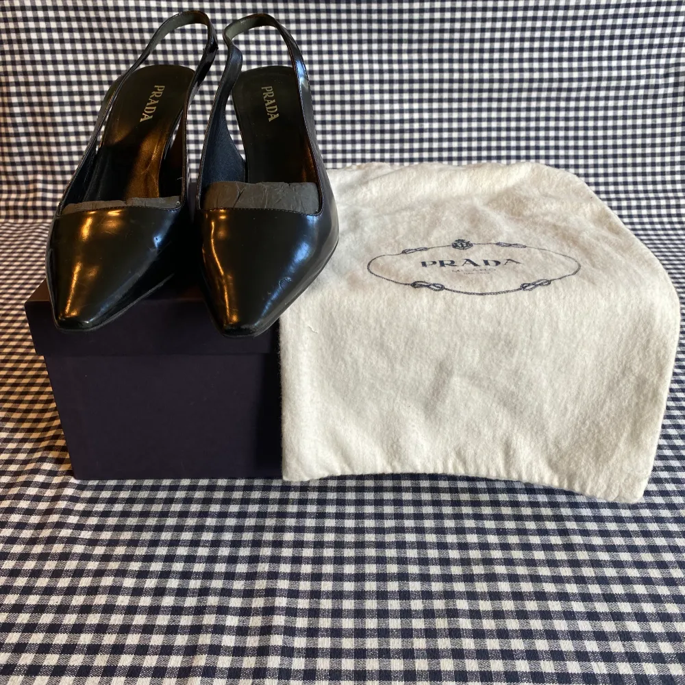 Svarta läder slingback klackskor ifrån Prada (7 cm klack). Skorna är i gott skick. Orginal skopåse och kartong medföljer.. Skor.