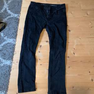Ett par svart jeans, mid waist, slits nere vid anklarna, lite utslitna