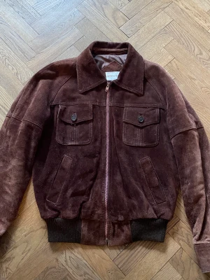 Vintage Stilig Mocka Jacka - Riktigt stilig mocka jacka, i brun mocka, den är nog minst 15 år gammal men i sjukt bra skick!  Den väger nog minst 2kg och är en riktigt tung jacka.   Den är en gammal jacka som har funnits i familjen men nu vid utrensning så åker den dessvärre