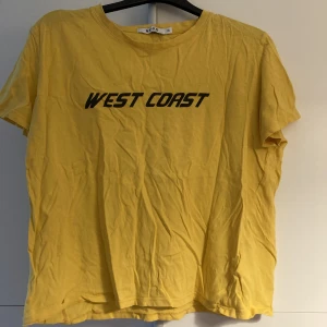 T-shirt - Gul t-shirt från NAKD med svart tryck. Stryks innan den skickas