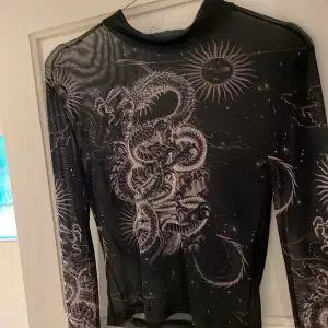 Långärmad svart mesh tröja med tryck på framsida och armar. 