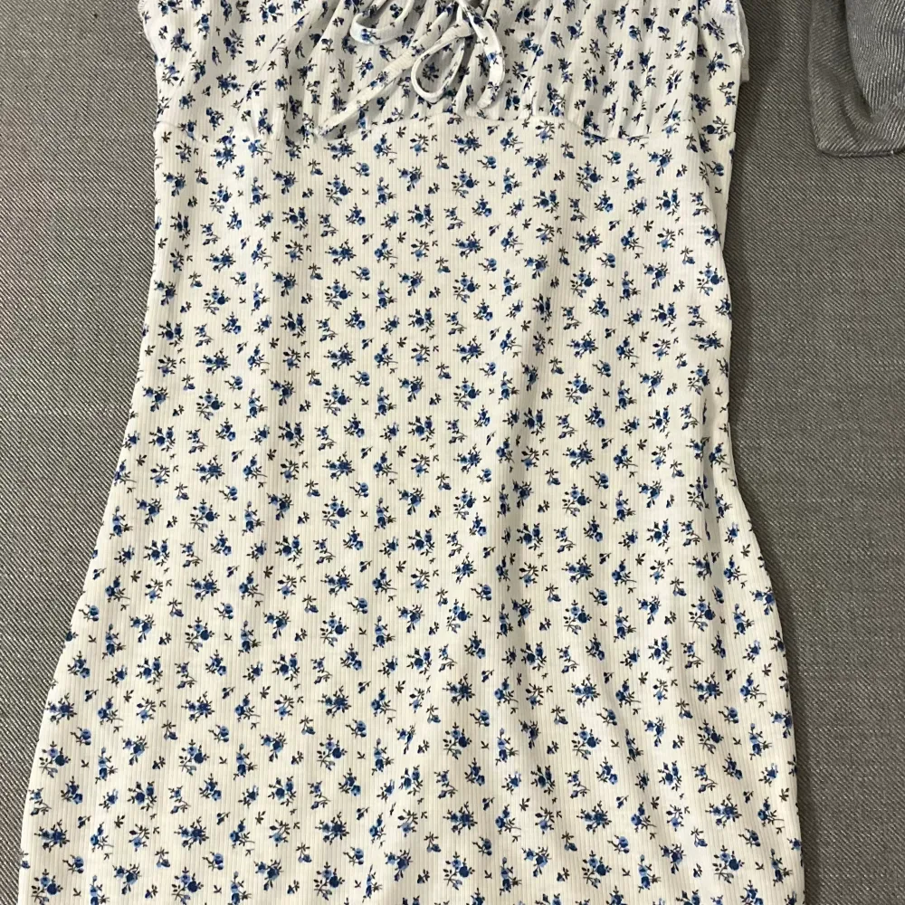 Kort klänning som är vit med blåa blommor. . Klänningar.