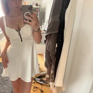 Vit klänning - Supersöt vit klänning till sommaren med dragkedja framtill som går att reglera. Vaddering i brösten så BH behövs inte under. Köpt i Italien men passar en XS-S/ liten M. Använd 2 gånger. 