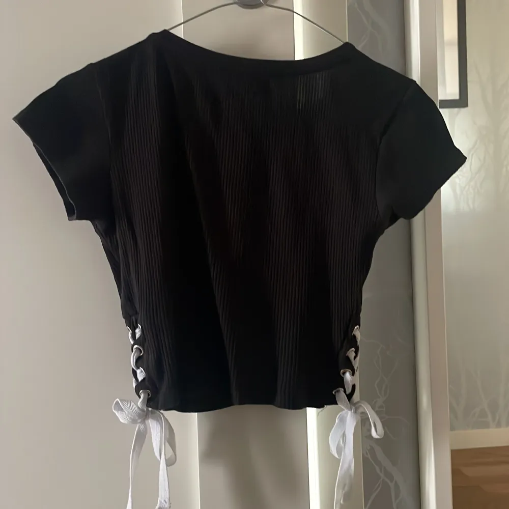 Ribbat material med mycket stretch, knytdetaljer på sidan som man själv kan reglera och knyta efter tycke.. T-paidat.