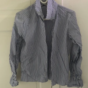 Randig skjorta med volangarmar - Blå och vitrandig skjorta med volangarmar från piedestalen, storlek xs, enbart använd 3 gånger