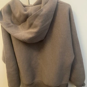 Stickad hoodie  - Stickad hoodie köpt på Åhléns för ett år sedan, knappt använd! Det finns en ”slits” runt midjan som går att vika upp som jag gjort på bilden