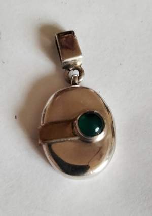 Liten silvermedaljong med grön onyx . Inte öppningsbar. Aldrig använd 2'5 cm lång inkl hänget.  