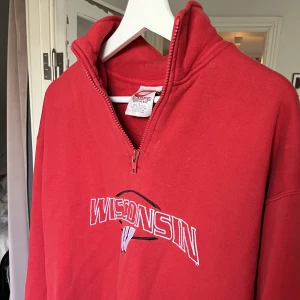 Röd Wisconsin 1/3 zip sweatshirt  - En röd jätte skön 1/3 zip sweatshirt men Wisconsin på bröstet, står i storlek L men passar även som lite baggy M, inga märkbara defekter bortsätt från att plagget är begagnat men annars i väldigt fint schick. Skriv vid funderingar
