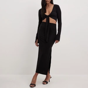 Ribbat set - Säljer mitt ribbade set med knyttopp och långkjol från NA-KD. I nyskick. Storlek M i toppen och S i kjolen. 