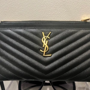 Yves saint Laurent väska, som ny! - Köpte den i nyskick begagnad… och har endast använt den 2 ggr:) 22,5 x 12,5 cm, dragkedja.