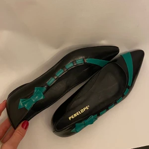 Ballerinaskor med rosett - Superfina ballerinaskor med en grön rosett och lite spetsigare tå. Märke: Penelope. Storlek: 39/40 