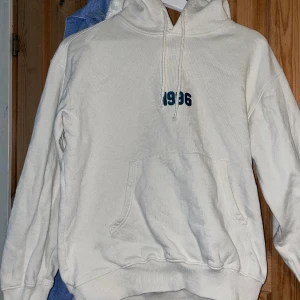 Vit Hoodie med print på ryggen - Vit Hoodie med grön brodyr på framsidan och grönt tryck på ryggen, köptes på carlings men har knappt använts efter det. Tröjan är liten i storlek enligt mig. Kan mötas i Västerås eller fraktas mot att köparen står för frakten.