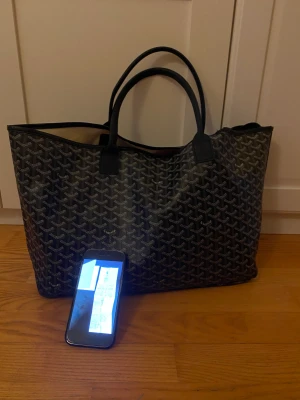 Goyard väska - Goyardväska originellt köpt från en Vintage affär för ca 15000kr. Kvitto finns från tidigare ägaren digitalt. Använt skick vänligen se bild 3. Orginalhandtag uttbytta av tidigare ägare då de gick sönder, till nya läderhandtag.