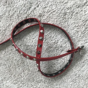 Rött nitbälte - Rött smalt nitbälte🖤 Knappt använd! 95cm långt men går såklart att justera  till ganska litet. Har ett litet hack i materialet vid hålen som knappt syns🌱 går också att använda som choker/armband🌙
