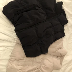 Pufferväst Svart & Beige - Nyskick - Två st puffervästar i storlek L, dem är rätt små i storleken så L är mer som S/M. Originalpris var 199 kr/st. Säljer båda för 89.