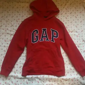 Röd gap hoodie med blå text. Den är i storlek xl barn storlek så skulle säga att den passar ungefär xs-s. 🤍