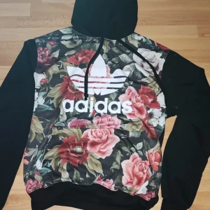 Blommig adidas tjocktröja - Adidas tjocktröja med blommor på framsidan. Skriv för mer bilder