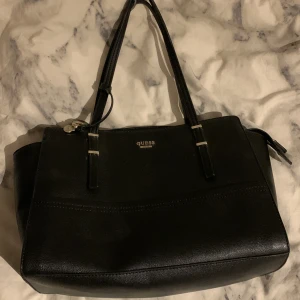 Väska  - Säljer denna jättefina guess väska pågrund av att den inte kommer till användning längre! Måtten är 34 x 26! Nypris 1 800