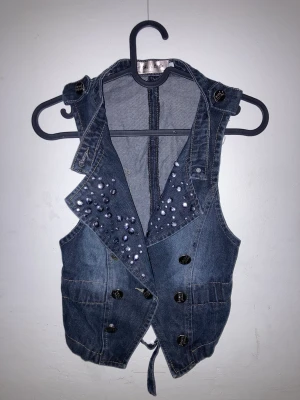 Jeansväst med nitar - Så cool jeansväst med urringning & nitar! Säljer då den tyvärr inte kommer till användning. Några nitar har ramlat av men tycker inte det märks, pris kan alltid diskuteras!❤️🎀