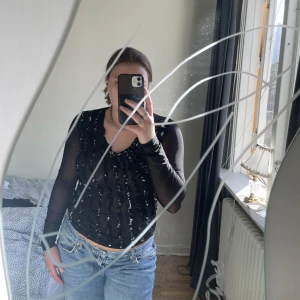 Mesh tröja - Svart meshtopp med vita volanger. Så fin!