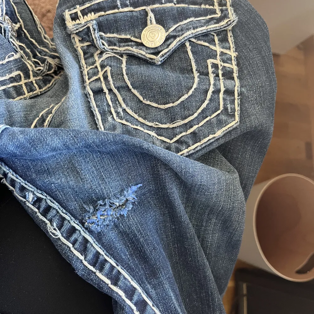 Så fina True Religion jeans som tyvärr är för små för mig😢De är i bra skick, men det finns ett hål (bild 3) inget man tänker på eller syns när man har på sig dom dock! De är i bootcut och lågmidjad modell. Midjemått: 38cm, Innerbensmåttet: 83cm.. Jeans & Byxor.