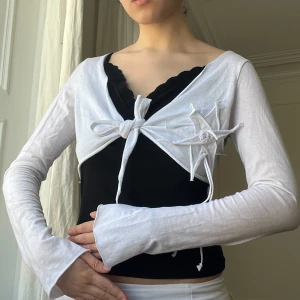 Vit bolero med blomma - Storlek S. Hade ett litet hål på baksidan men det har sytts ihop, inget man märker när man har på sig den. Möts i stockholm eller fraktar 🎀