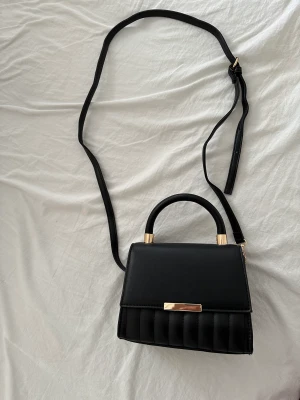 Väska  - Helt ny oanvänd väska i svart med guld detaljer 