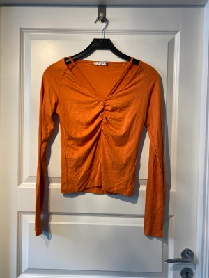 Orange topp - Långärmad tröja i storlek S. Väldigt mjukt och töjbart material! Detaljer över brösten. Aldrig använd.   Mått:  Armlängd: från Axel 70cn Längd: 53 cm Bredd över byst: 36cm