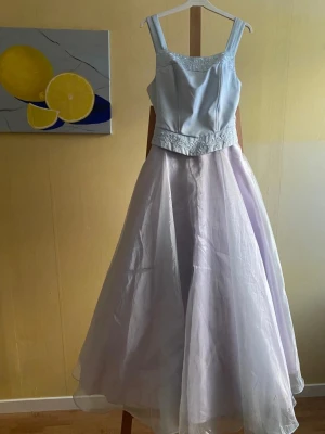 Ljusblå Balklänning  - Ljusblå aftonklänning med askungekänsla. Matchande sjal medföljer. Dold dragkedja baktill  Märke: Poly Tillverkad i USA Storlek: M  passar  för en person för ca 160-170 cm lång.  Använd två gånger, som ny. 