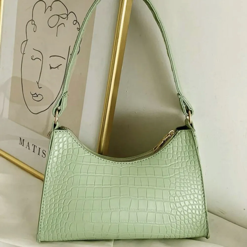 En grön handväska i ”ormskinn” med en guld dragkedja. Hör av er vid frågor och vid snabb affär kan priset sänkas:). Väskor.