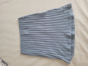 Sommarkjol - En ljusblå sommarkjol i tight modell som är kortare fram och längre bak. Kjolen sitter ganska tight på mig som har medium men skulle funka på en small eller large också! Helt oanvänd. 