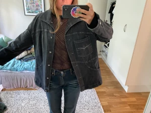 Svart jeansjacka oversize - Hallå!!! Hur unik och cool är inte denna svarta/mörkgråa jeansjacka. Så coola stendetaljer och perfekt oversize fit. Helt i nyskick. Köpt för 900kr❤️