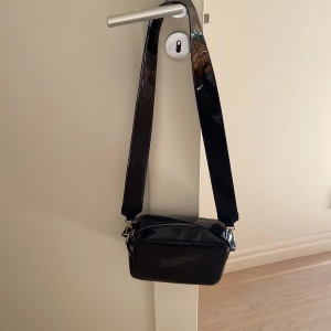 Lackerad axelremsväska - Edgy, snygg och praktisk! Passar till allt. 
